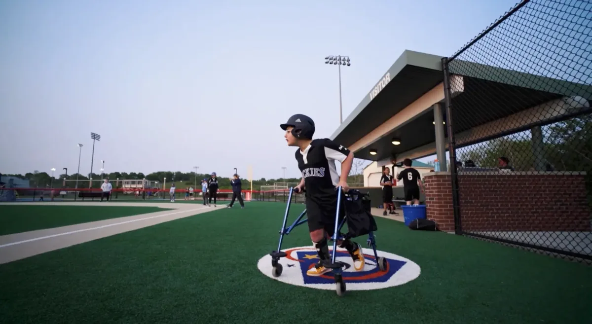 A young athlete using a walker steps onto the field at a Casey's Clubhouse game