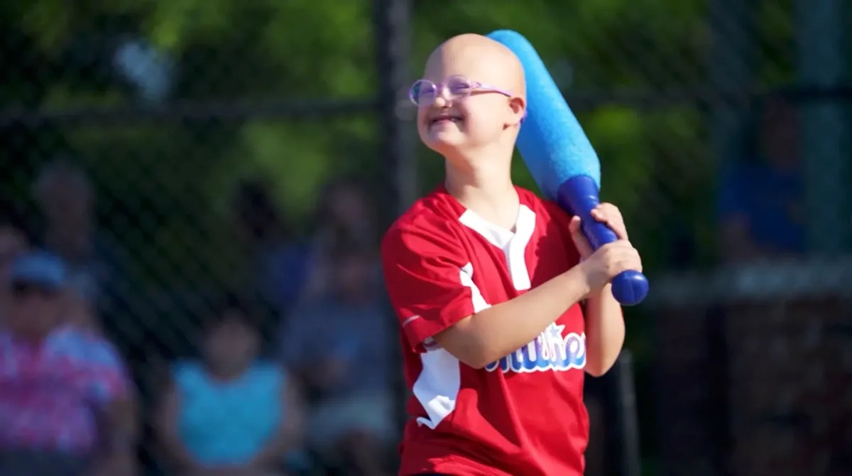 A smiling young Casey's Clubhouse player at bat